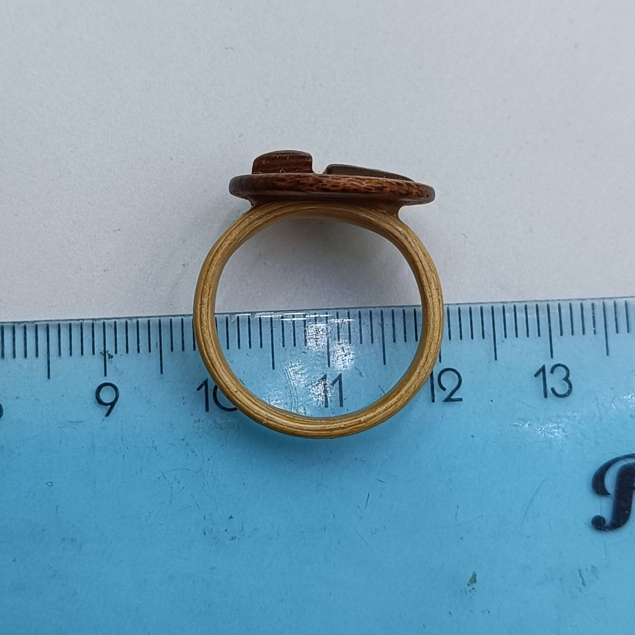 Wooden ring on a blue ruler against a white background